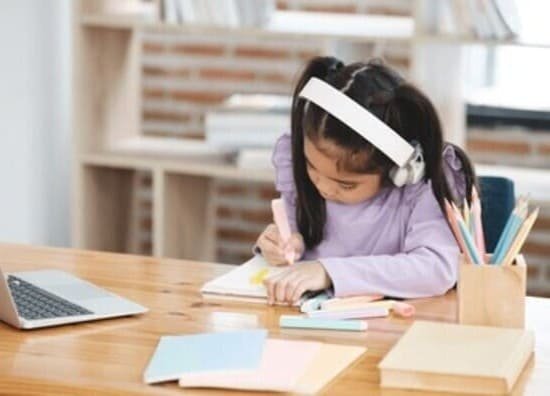 Girl with headphones drawing in notebook, student studying