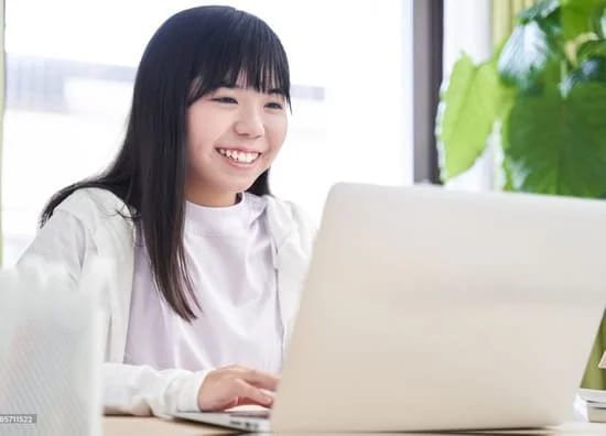 Smiling junior high girl at laptop for online English lesson.