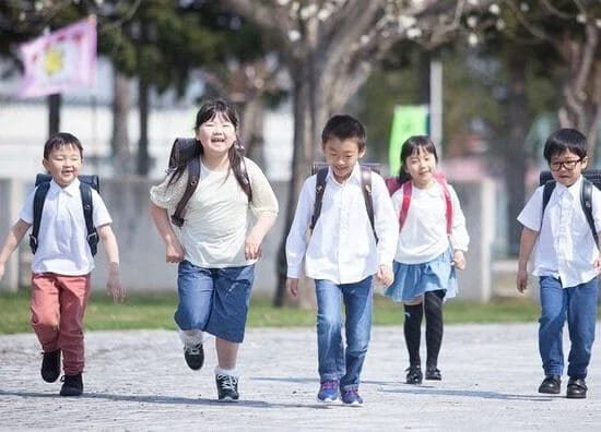 Elementary school children walking with backpacks on the way to school.