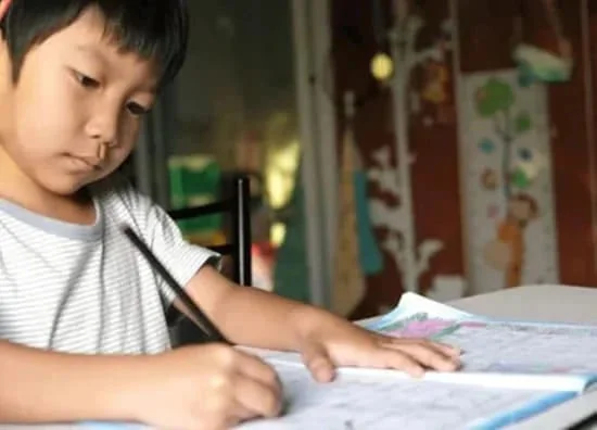 ノートに英語を書きながら勉強する小学生の男の子