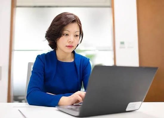 オフィスでノートパソコンを使って仕事をするビジネス女性。